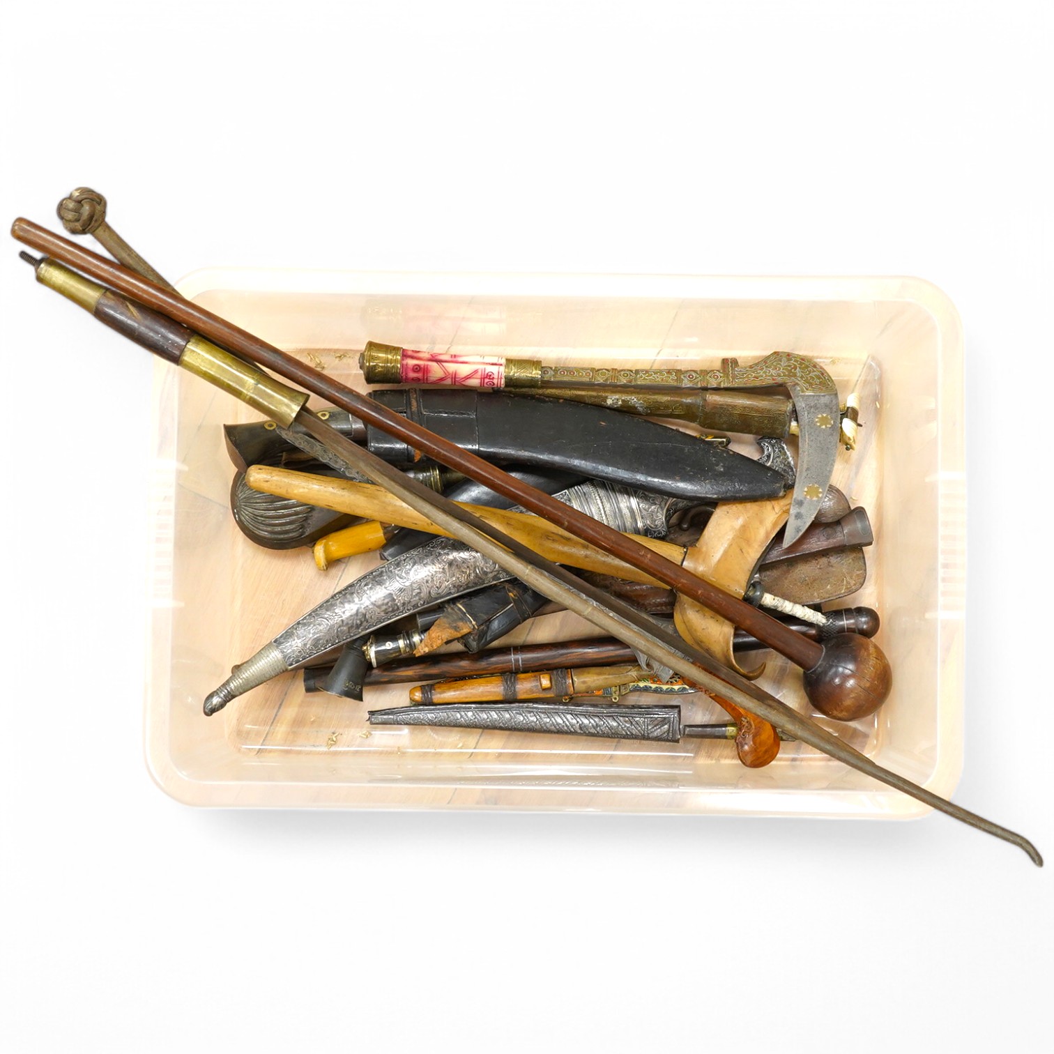Eighteen assorted world weapons comprising a silver jambya (pommel missing), a knobkerry, a dha, two kris (one with handle missing), a lohar, three kukris, a djambok, a Chinese trousse, a chora, a flyssa, five others and
